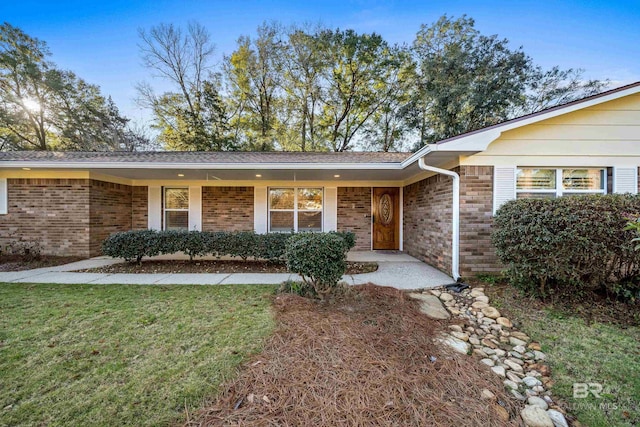 ranch-style home with a front yard and brick siding