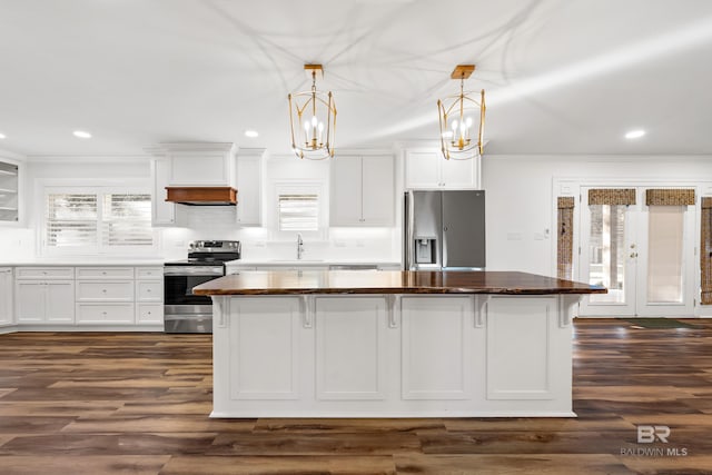 kitchen with stainless steel appliances, a breakfast bar, a kitchen island, and white cabinetry