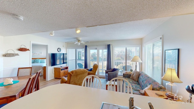 dining room with a textured ceiling, ceiling fan, and light wood-type flooring