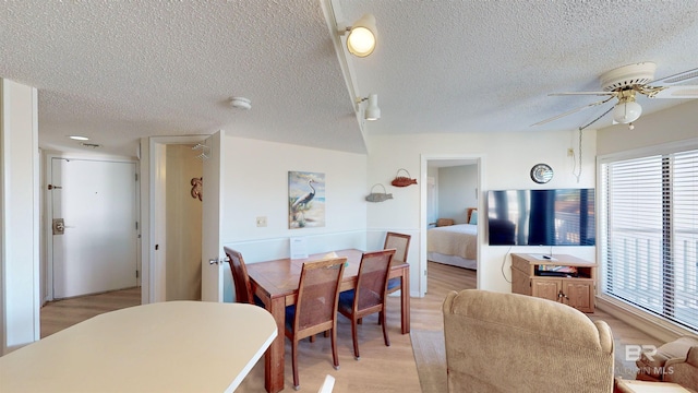 dining space featuring ceiling fan, light wood-type flooring, and a textured ceiling