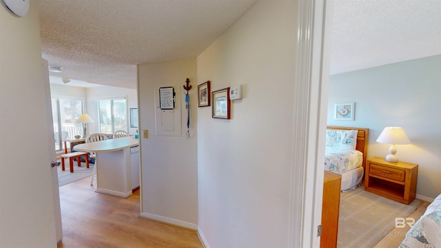 hallway featuring a textured ceiling and light hardwood / wood-style flooring