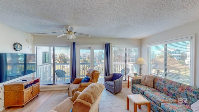 living room with ceiling fan, light hardwood / wood-style floors, and a textured ceiling