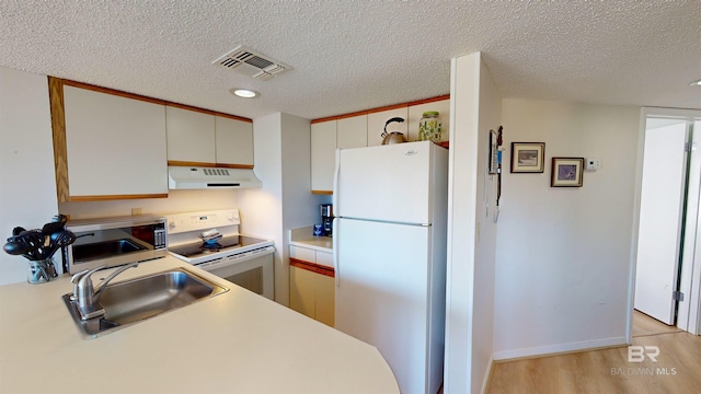 kitchen featuring light hardwood / wood-style floors, sink, white appliances, a textured ceiling, and white cabinets