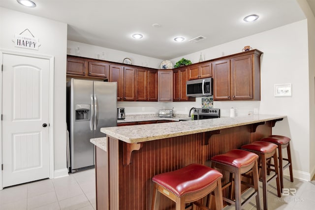 21105 Zinfandel Ln, Silverhill, AL 36576 - kitchen with a peninsula, appliances with stainless steel finishes, light tile patterned flooring, and a breakfast bar area