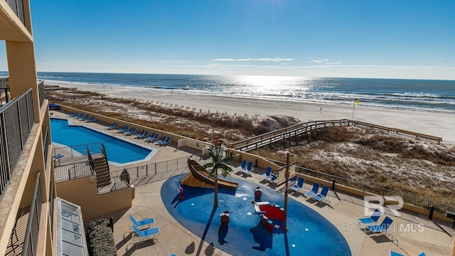 view of swimming pool with a water view, a beach view, and a water play area