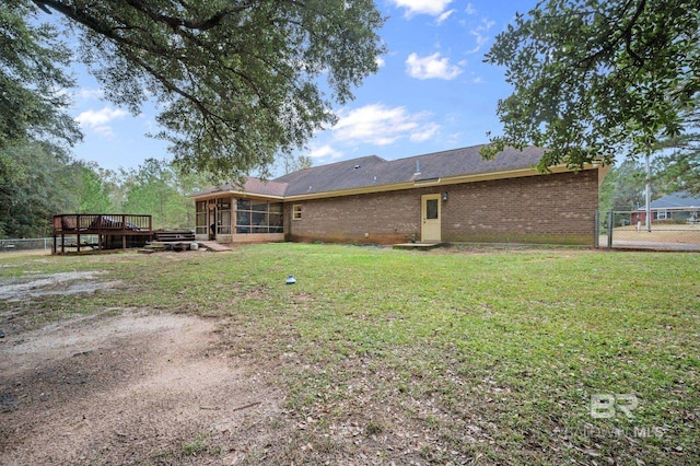 back of property featuring a yard, a sunroom, and a wooden deck