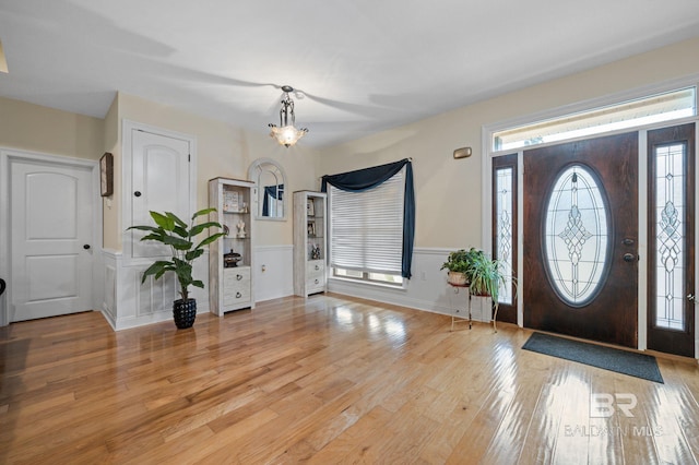 foyer entrance with light wood-type flooring and a notable chandelier