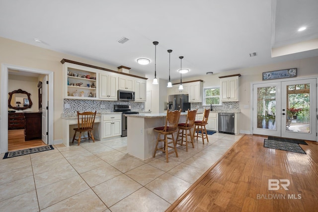 kitchen featuring light stone counters, french doors, a breakfast bar, a kitchen island, and appliances with stainless steel finishes