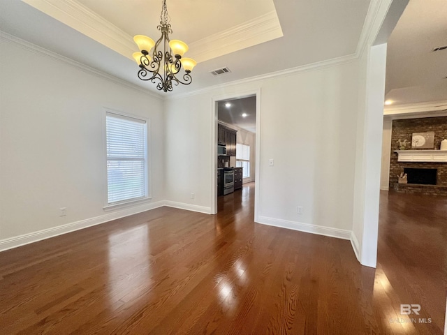 unfurnished dining area featuring visible vents, a raised ceiling, dark wood finished floors, ornamental molding, and an inviting chandelier