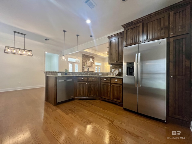 kitchen featuring visible vents, stainless steel appliances, a peninsula, and decorative light fixtures