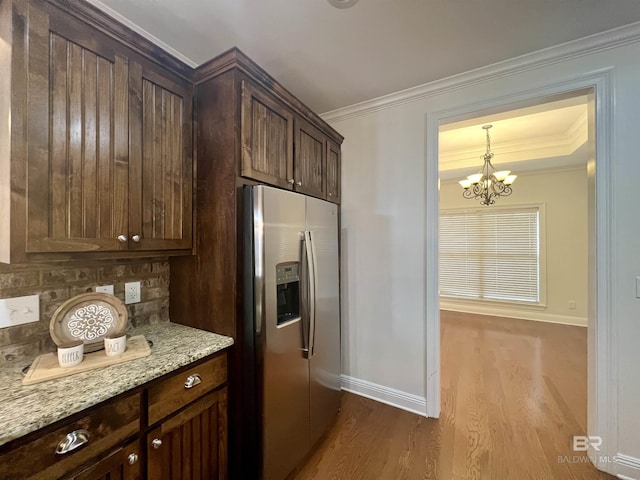 kitchen with light stone counters, stainless steel refrigerator with ice dispenser, wood finished floors, and crown molding