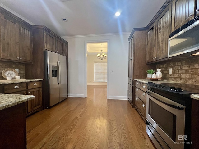 kitchen with light stone counters, dark brown cabinets, appliances with stainless steel finishes, tasteful backsplash, and crown molding