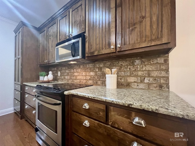 kitchen with stainless steel appliances, dark wood-style flooring, dark brown cabinets, light stone countertops, and tasteful backsplash