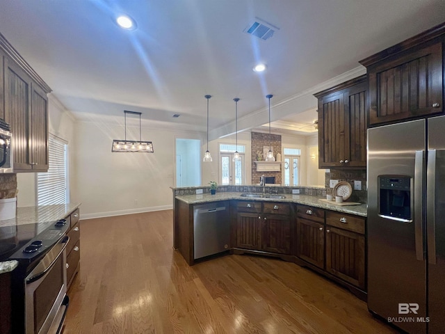 kitchen with a peninsula, visible vents, stainless steel appliances, and decorative light fixtures