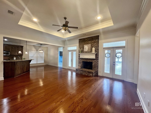 unfurnished living room featuring plenty of natural light, a raised ceiling, and french doors