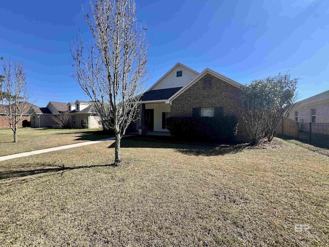 view of front facade featuring brick siding, fence, and a front lawn