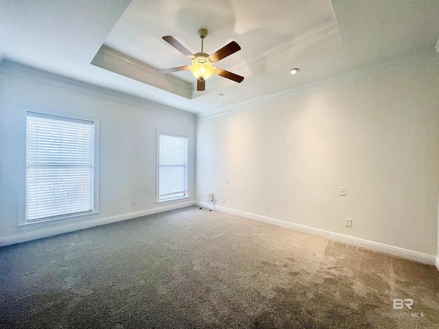 carpeted spare room featuring ornamental molding, a tray ceiling, ceiling fan, and baseboards