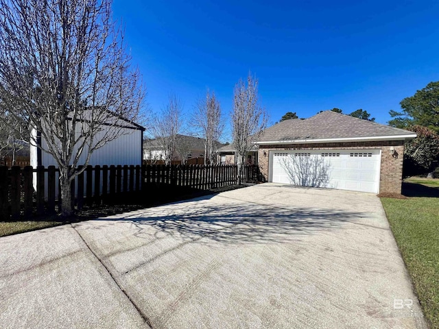 view of property exterior featuring driveway, brick siding, a shingled roof, and fence