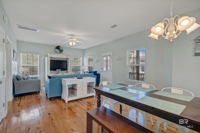 dining room featuring light wood-style flooring, ceiling fan with notable chandelier, and visible vents