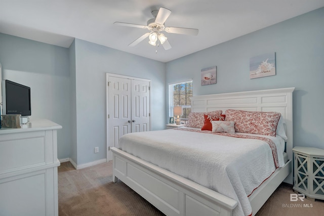 bedroom featuring a closet, baseboards, light colored carpet, and ceiling fan