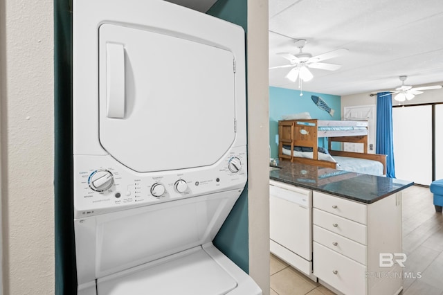 washroom with ceiling fan, stacked washer and clothes dryer, and light tile patterned flooring