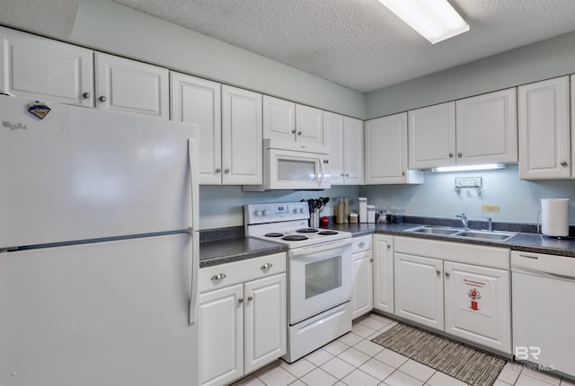 kitchen featuring dark countertops, white cabinetry, a sink, a textured ceiling, and white appliances