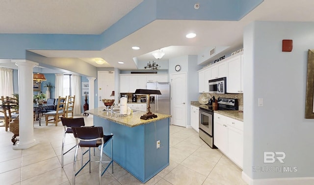 29235 Perdido Beach Blvd Unit 203, Orange Beach, AL 36561 - kitchen with appliances with stainless steel finishes, ornate columns, tasteful backsplash, light tile patterned flooring, and a kitchen breakfast bar
