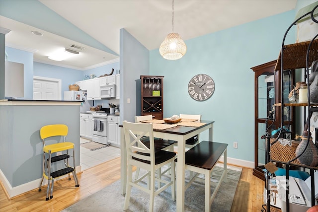 dining area featuring ornamental molding, light wood-type flooring, and lofted ceiling