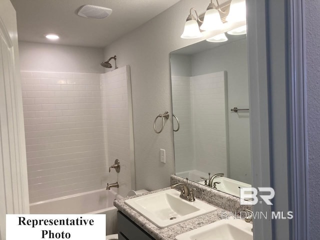 bathroom with tiled shower / bath combo and vanity