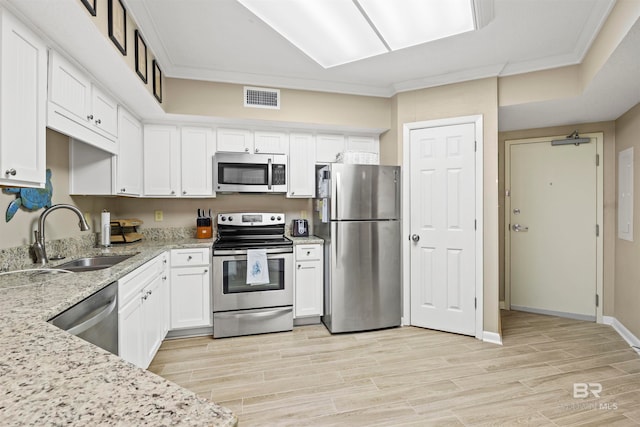 kitchen with sink, light hardwood / wood-style flooring, white cabinetry, appliances with stainless steel finishes, and light stone countertops