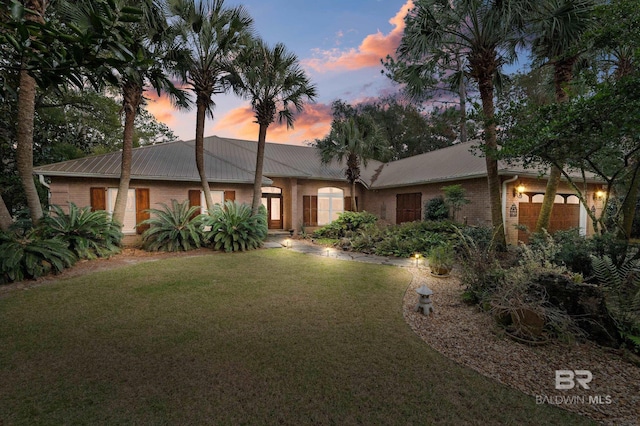 ranch-style house with a garage and a lawn