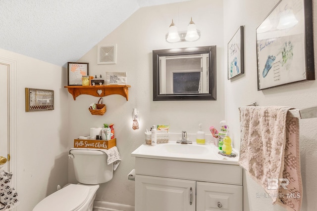 bathroom with vanity, lofted ceiling, a textured ceiling, and toilet