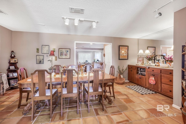 dining area with rail lighting and a textured ceiling