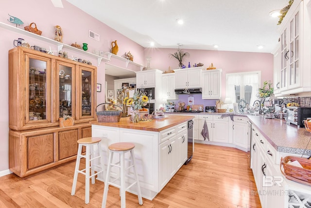 kitchen with a center island, white cabinets, a breakfast bar, and light hardwood / wood-style flooring