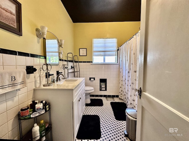 bathroom with a shower with curtain, vanity, tile walls, tile patterned flooring, and toilet