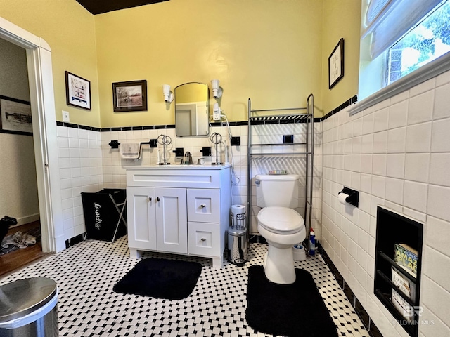 bathroom with tile patterned flooring, vanity, toilet, and tile walls