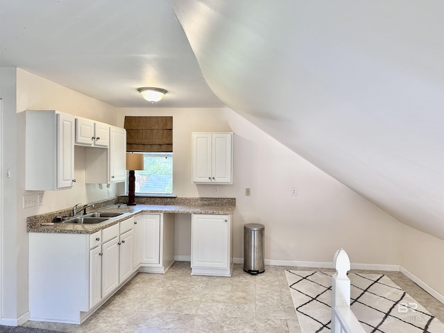 kitchen featuring white cabinets, vaulted ceiling, and sink