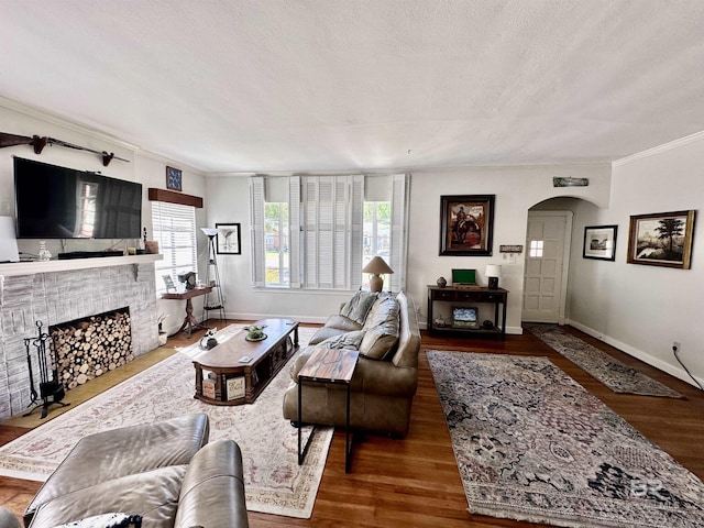 living room featuring a textured ceiling, wood-type flooring, and ornamental molding