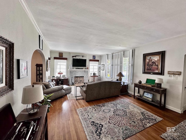 living room featuring a textured ceiling, wood-type flooring, and crown molding