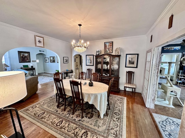 dining room with hardwood / wood-style flooring, ornamental molding, and an inviting chandelier