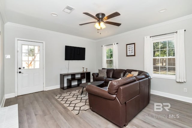 living room with a healthy amount of sunlight, visible vents, and crown molding