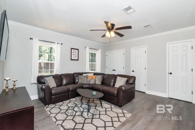 living area featuring wood finished floors, visible vents, and crown molding