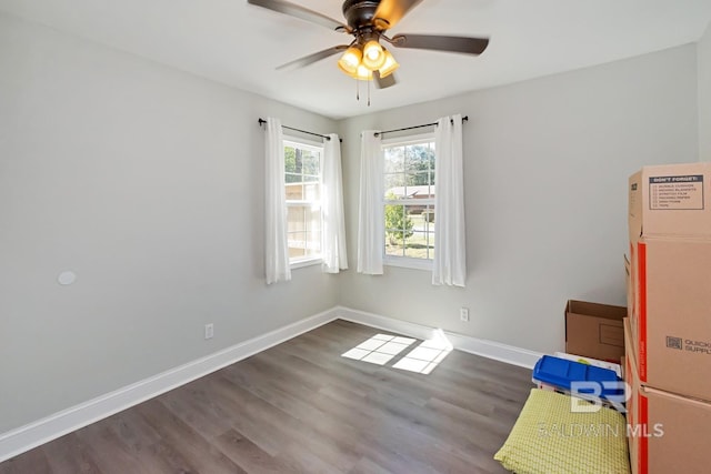 spare room with wood finished floors, a ceiling fan, and baseboards