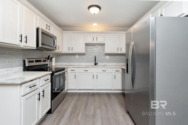 kitchen with stainless steel appliances, white cabinetry, and a sink