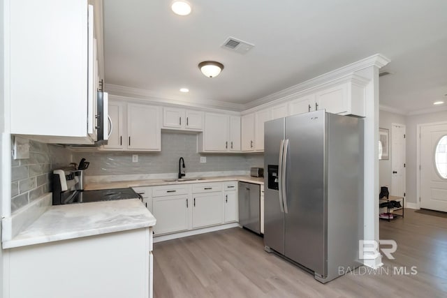 kitchen featuring visible vents, appliances with stainless steel finishes, crown molding, white cabinetry, and a sink