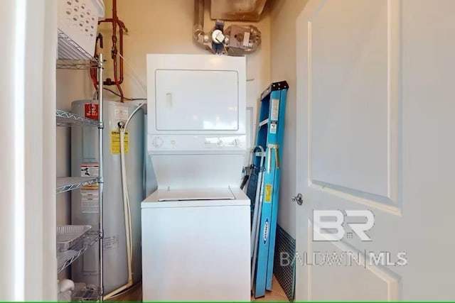 laundry area with laundry area, water heater, and stacked washer and clothes dryer