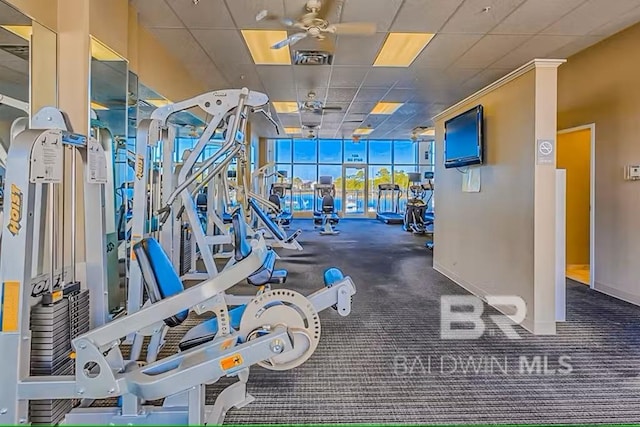 exercise room featuring a drop ceiling, ceiling fan, and baseboards