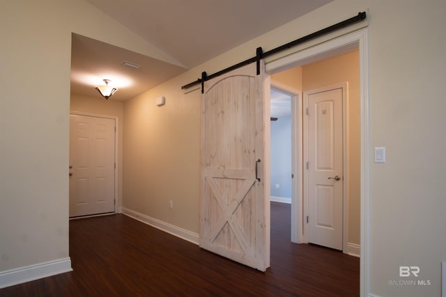 empty room featuring dark hardwood / wood-style floors, a barn door, and lofted ceiling