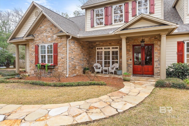 view of front of home with a front lawn, covered porch, and french doors