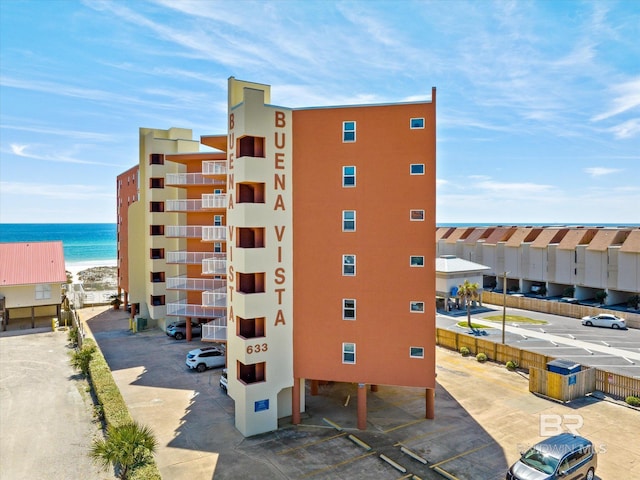 view of building exterior featuring uncovered parking and a water view